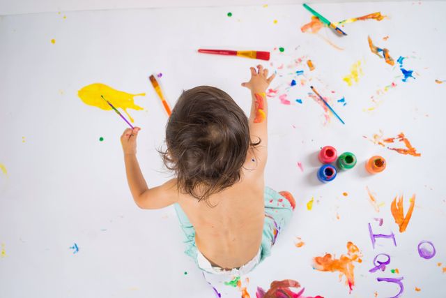 pexels-photo-40103784-40103784 A child artist expressing creativity with vivid colors on a large canvas using finger paints.
