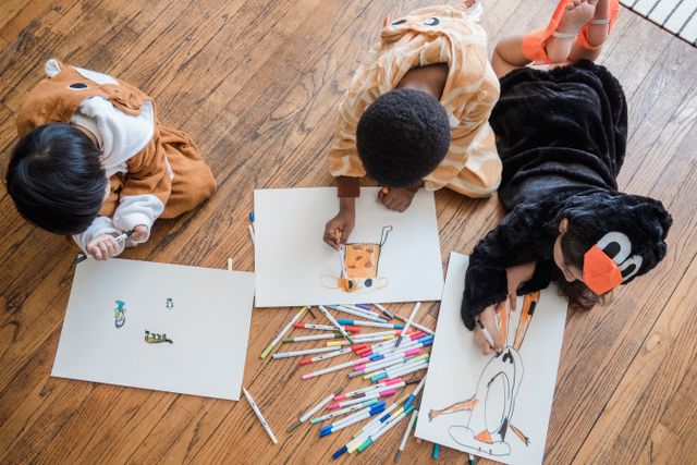 Kids in animal costumes having fun drawing on the floor.